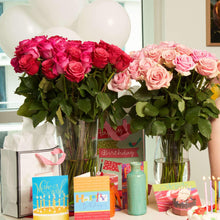 hot pink & bicolor pink roses in a glass vase on a table with celebration material
