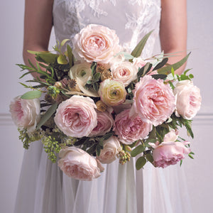 Bride holding a bouquet of Keira roses - Frilly wedding-dress petals frame her cupped blooms in every shade of soft pink, from raspberry ripple to clotted cream. 